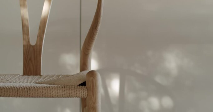 Wooden chair seat made of natural fibers and a light wooden frame. Sunlight casts shadows across the chair, creating a warm, inviting atmosphere. Perfect for interior design or furniture projects.