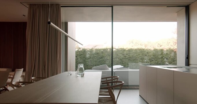 Modern dining room with glass sliding doors opens to patio, wooden table, and minimal interior design. peaceful ambiance. contemporary living and interior design