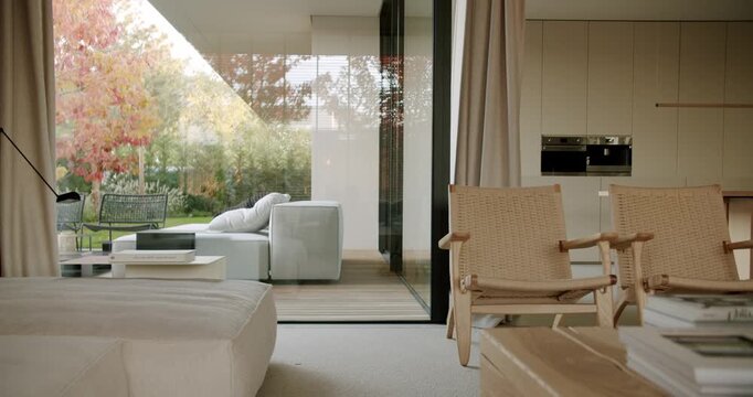 Modern living room interior with comfortable furniture and large windows overlooking a beautiful garden. Natural light fills the room creating a cozy and relaxing atmosphere.