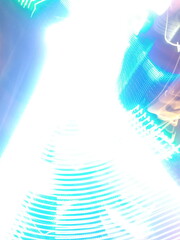 Colorful, fluorescent swirls of light create a dynamic and energetic abstract composition. Blurred streaks of purple, blue, and gold give the impression of rapid, surreal movement.