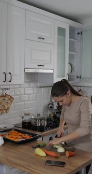 Girl cooking in the kitchen. Cutting vegetables with a knife. Preparing vegetables for baking in the oven.