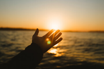 Reaching for the golden sun at dawn, feeling hope and new beginnings over the tranquil water's edge