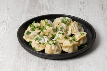 Delicious dumplings served with fresh herbs on a dark plate, perfect for a cozy meal at home
