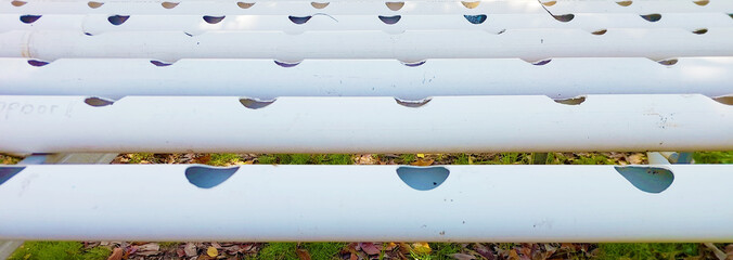 Horizontal view of white PVC pipes for a hydroponic gardening system with planting holes.