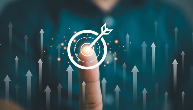 Finger touching digital bullseye interface with glowing arrow, symbolizing business growth, innovation, success, and achievement, with upward arrows in background