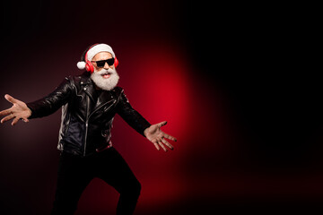 Santa rocker in leather jacket with red headphones performs on a dark stage for a Christmas vibe