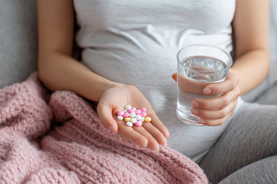 Pregnant woman holding vitamins and a glass of water promoting prenatal health and pregnancy care