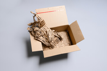 Opened cardboard box filled with shredded corrugated cardboard cuttings showing eco-friendly recycled filler material from cutting machine for sustainable packaging