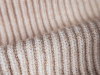 close up of beige ribbed knit texture with gentle fold and soft focus background