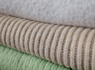 macro stack of rolled fabrics: white fleece, beige ribbed knit and pale green texture
