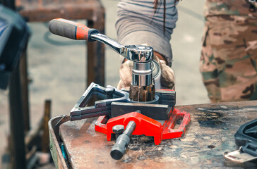 Male hands in gloves fix part for welding. Welding vice.with screw handle and cast iron frame