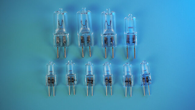 halogen capsule lamps G6.35 and G4 in two rows on a blue background. Glass flasks, a bipin base, object photography from above.