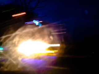 The glossy, reflective surface reflects intense light with a spectrum of bright colors such as purple, orange, and green, creating a dynamic and surreal abstract scene.