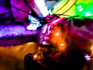 The glossy, reflective surface reflects intense light with a spectrum of bright colors such as purple, orange, and green, creating a dynamic and surreal abstract scene.