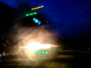 The glossy, reflective surface reflects intense light with a spectrum of bright colors such as purple, orange, and green, creating a dynamic and surreal abstract scene.