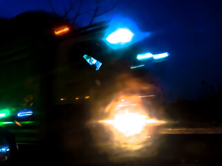 The glossy, reflective surface reflects intense light with a spectrum of bright colors such as purple, orange, and green, creating a dynamic and surreal abstract scene.