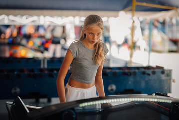 Focused girl playing air hockey at amusement park