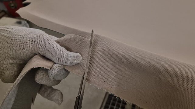 Fabric cutting textile industry manual work worker trims excess material with scissors manufacturing process