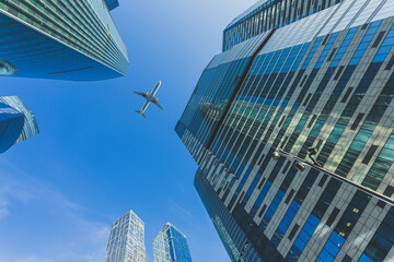 Modern glass skyscrapers on a clear day and passenger airliner fly over