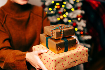Christmas presents wrapped in festive paper in the hands of a female