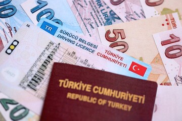 Turkiye driving permit concept. Driver license with passport and turkish liras money bills close up