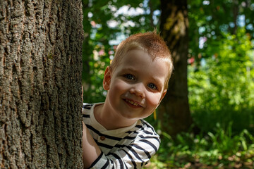 A cute smiling blue-eyed boy in a nature park.
