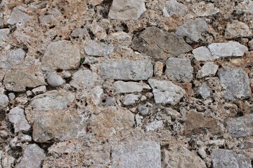 Close-up detailed texture of an ancient stone wall built with irregular rocks and mortar, showing weathered surfaces, natural tones, and rustic craftsmanship typical of medieval fortifications.