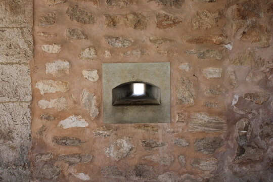 Small defensive window or arrow slit in a stone wall of the Castle of Santa Pola, Alicante, Spain. Showing historic architecture and textured masonry of the old fortress built in the 16th century.