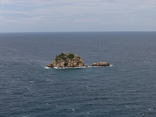 stormy sea backdrop with solitary stone, remote rocky outcrop amidst turbulent waves and gusts Koh Tao Thailand