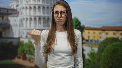 Fototapeta premium Woman points thumb at leaning tower building in pisa with a disgusted grimace; travel frustration annoyed.
