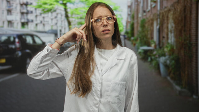Woman scientist points finger on city street wearing lab coat and glasses, bare hand visible; skepticism.