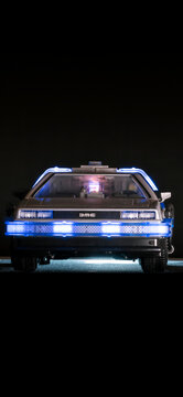 Madrid, Spain; October 25, 2025: Close-up front view of a Playmobil DeLorean toy inspired by Back to the Future, illuminated with blue LED lights on a dark background