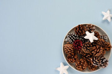 Pine cones and white stars in bowl on blue background