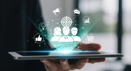 Targeted Audience Marketing: Hand Holding Tablet Displaying Group of People with Target Icon Surrounded by E-commerce and Communication Symbols for Business Strategy