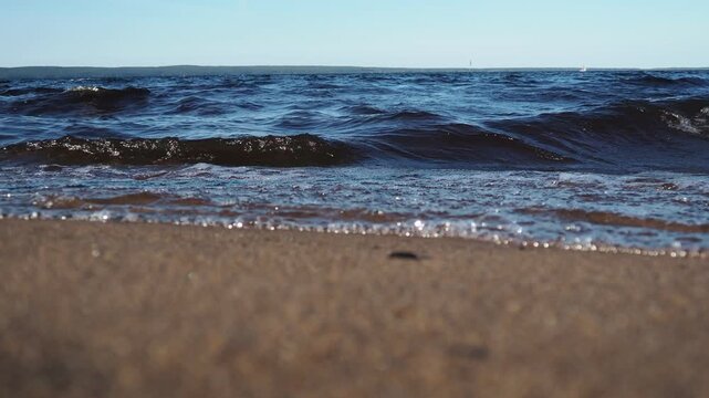Waves gently crash on shore of sandy beach at Lake Onego in Karelia. Scene captures beauty of nature and tranquility of water during sunset. Dark water with high iron content, sand containing shungite