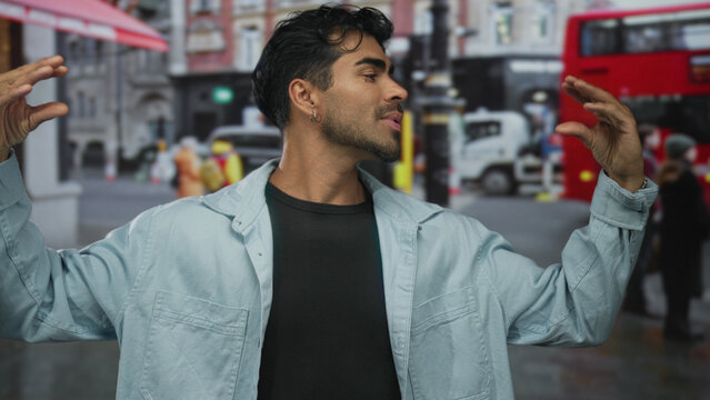 Young hispanic man speaking and gesturing with open hands on street; enthusiasm expression communication connection.