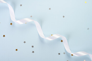 White ribbon and golden stars on blue background