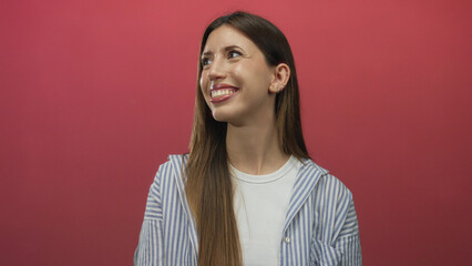 Young woman turns head upward showing glossy lips in pink studio with white and blue striped shirt; serenity.