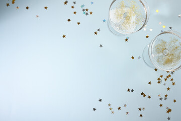 Champagne glasses with golden confetti on blue background
