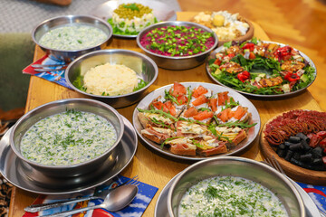 Olivier salad, sandwiches, canapés, bruschetta. A Christmas scene with meat delicacies against a dark wood background. An assortment of cheese and meat appetizers.