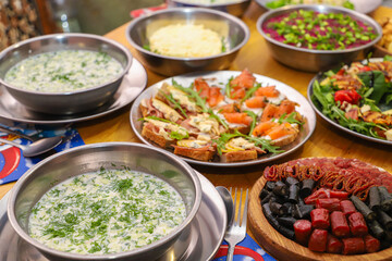 Olivier salad, sandwiches, canapés, bruschetta. A Christmas scene with meat delicacies against a dark wood background. An assortment of cheese and meat appetizers.