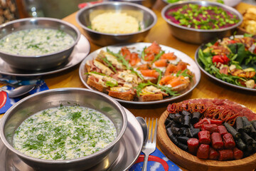 Olivier salad, sandwiches, canapés, bruschetta. A Christmas scene with meat delicacies against a dark wood background. An assortment of cheese and meat appetizers.