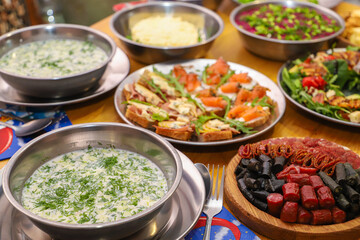 Olivier salad, sandwiches, canapés, bruschetta. A Christmas scene with meat delicacies against a dark wood background. An assortment of cheese and meat appetizers.