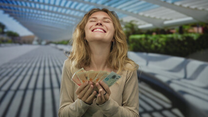 Woman fans banknotes while counting poland polish zloty as a blonde young smiling fan admires the display.