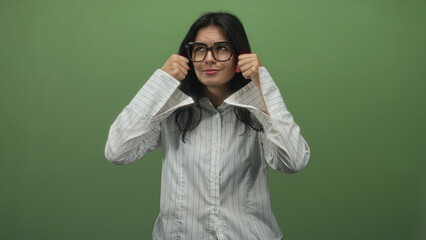 Young hispanic woman wearing oversized glasses and striped shirt makes crying gesture with hands in...