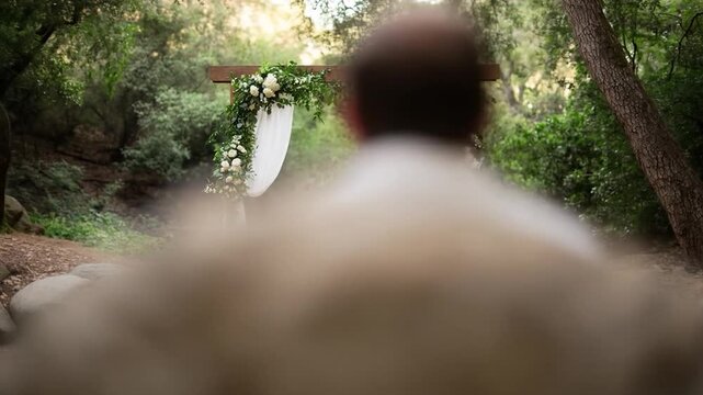 Outdoor woodland wedding ceremony arch decorated with white flowers and sheer fabric