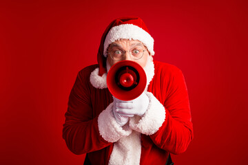 Santa with megaphone shouts festive message in bold red studio setting for Christmas and holiday season