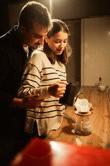 Loving couple hugging while making coffee at home kitchen evening
