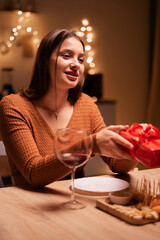 Happy young couple in love having dinner together celebrating Valentine's day at home, Love language - present giving, date at table.