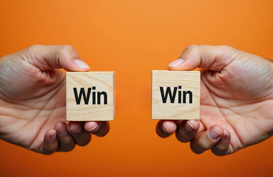Two hands hold wooden cubes with the word Win. Concept symbolizes mutual benefit and partnership. Represents successful cooperation. Achieving goals together.